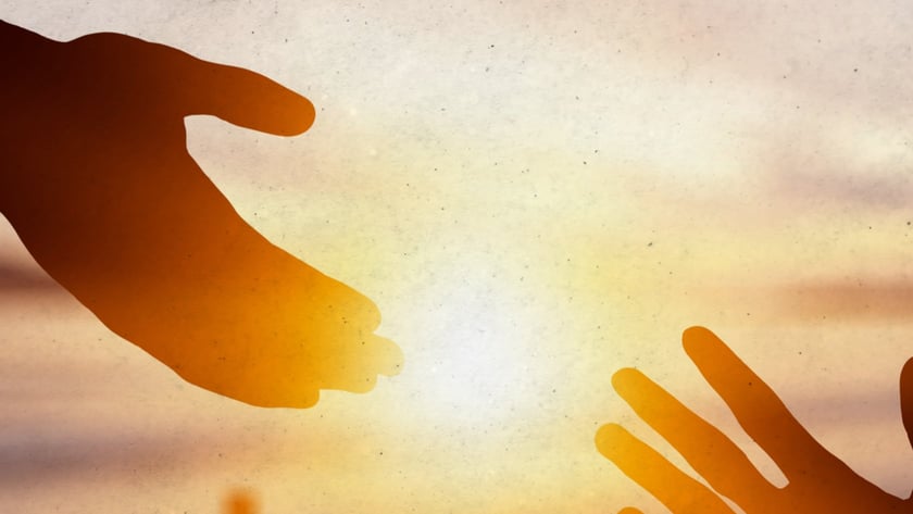 Duas mãos se estendem uma em direção à outra, com uma cruz ao fundo.