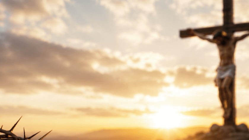 Crucifixo de madeira com Cristo em colina rochosa ao pôr do sol