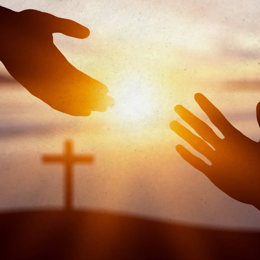 Duas mãos se estendem uma em direção à outra, com uma cruz ao fundo.