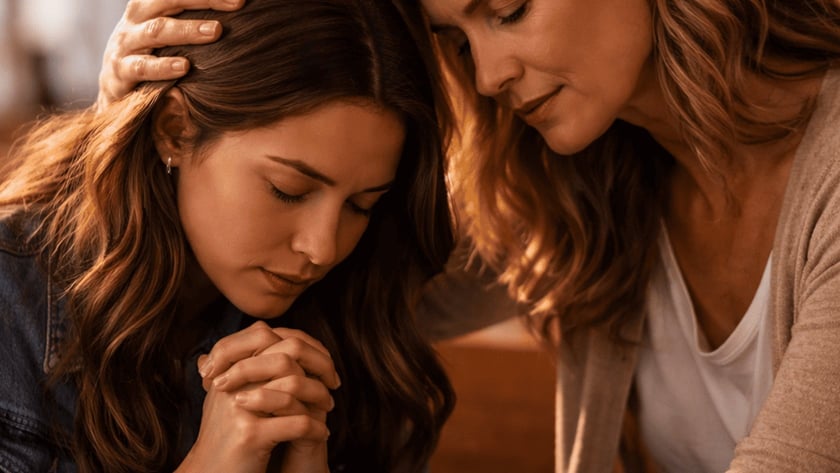 Duas mulheres em um banco de igreja, uma de mãos postas e a outra tocando sua cabeça.