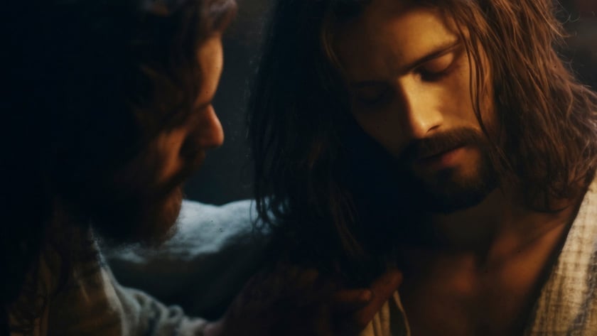Dois homens de cabelo comprido e barba, um deles apoia a mão no ombro do outro.