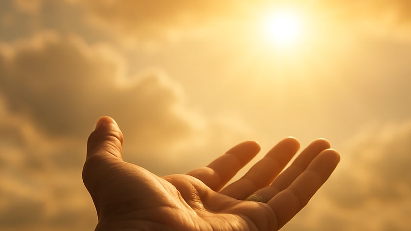 Mão aberta com a palma para cima, estendida em direção ao sol entre nuvens.