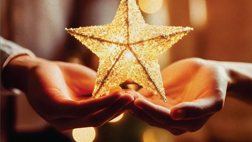 Duas mãos abertas seguram uma estrela dourada brilhante diante de luzes desfocadas.