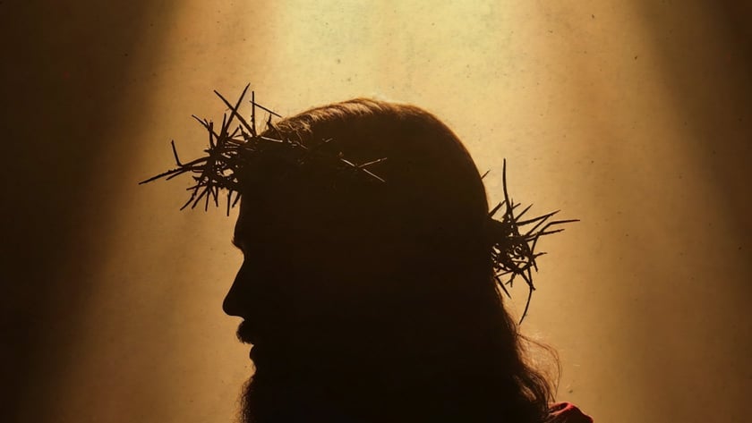 Silhueta de homem barbudo de perfil, com coroa de espinhos e manto avermelhado.