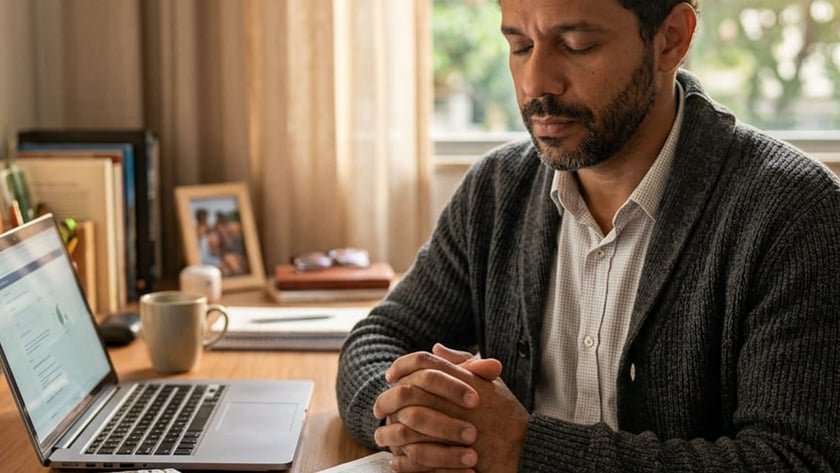 Homem de olhos fechados e mãos unidas diante de uma Bíblia aberta