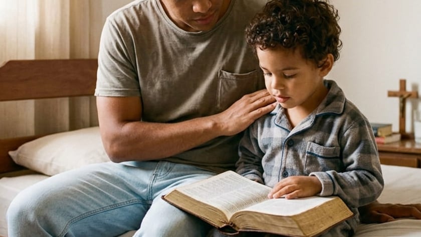 Homem e menino de pijama sentados numa cama, lendo juntos um livro grande aberto.