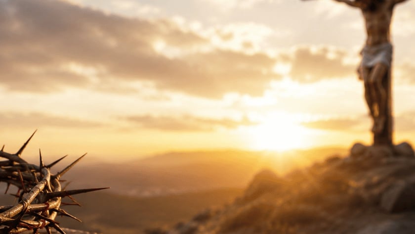 Crucifixo de madeira com Cristo em colina rochosa ao pôr do sol