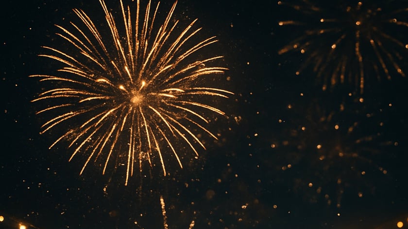 Fogos de artifício dourados explodem no céu noturno acima de um fio de luzes acesas.