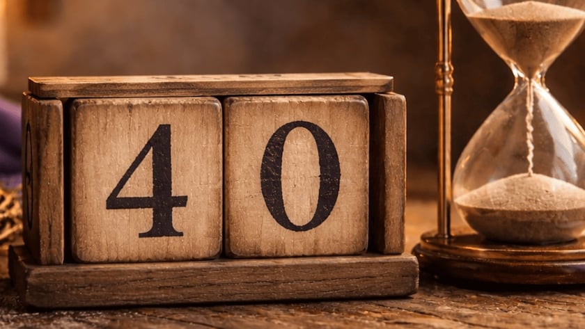 Ampulheta de latão ao lado de blocos de madeira com o número "40", sobre mesa rústica.