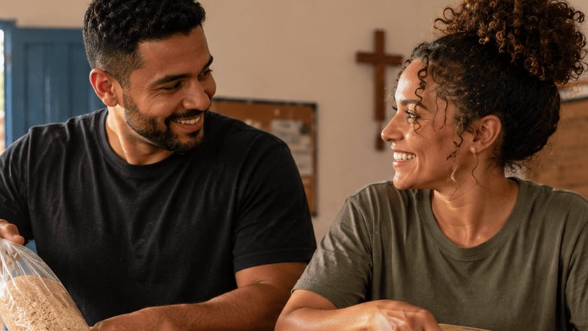 Dois voluntários sorridentes organizam alimentos em caixas de papelão