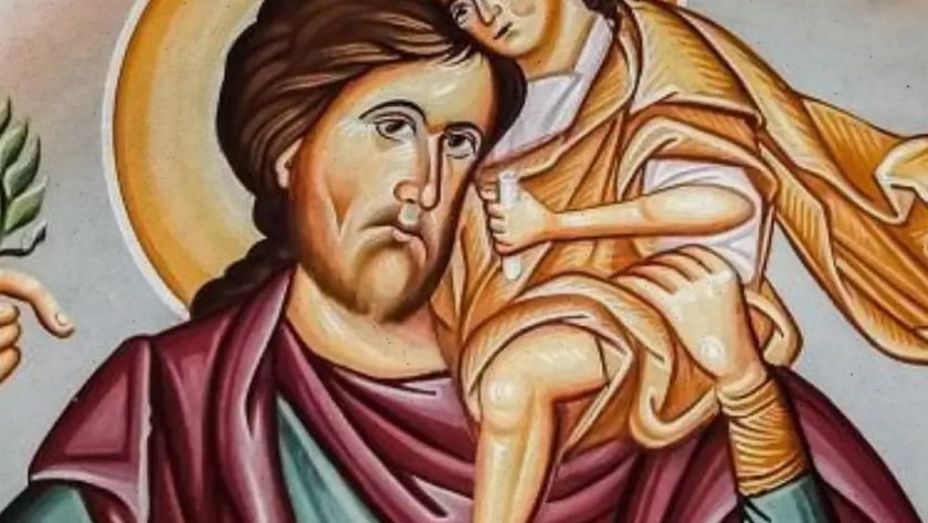Homem barbado com auréola carrega uma criança com auréola no ombro; texto "IC XC".
