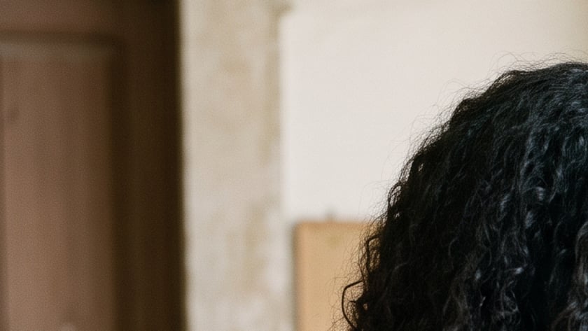 Mulher de cabelo cacheado com uma Bíblia sob o braço deposita algo em uma caixa de madeira. "Bíblia"