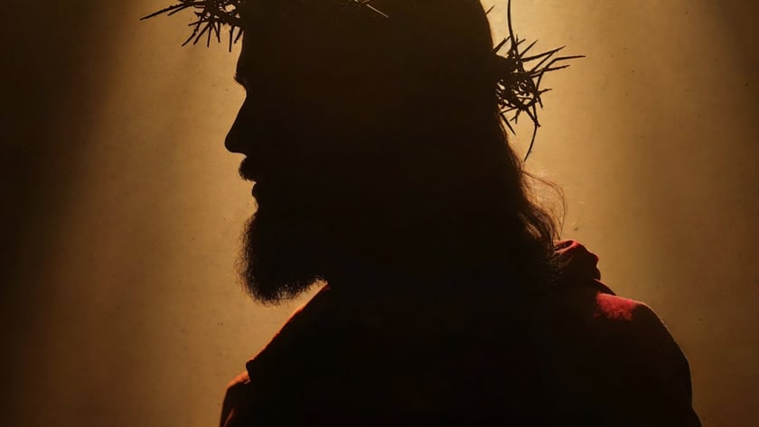 Silhueta de homem barbudo de perfil, com coroa de espinhos e manto avermelhado.