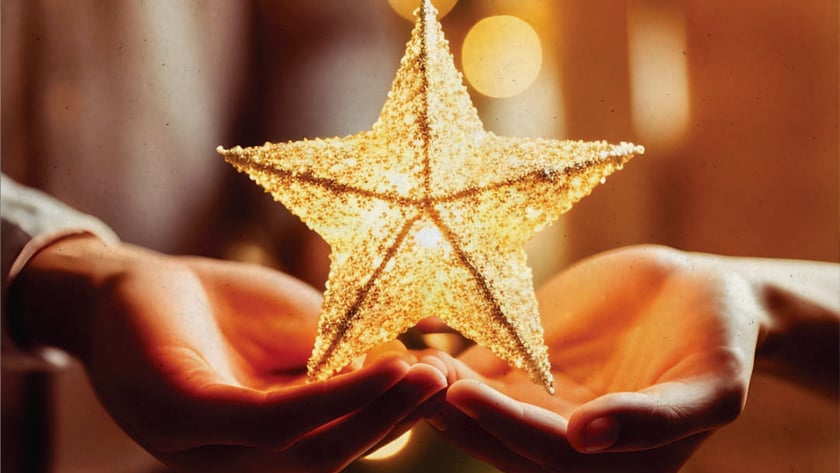 Duas mãos abertas seguram uma estrela dourada brilhante diante de luzes desfocadas.