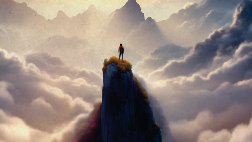 Pessoa de pé no topo de um pico rochoso, acima de nuvens e montanhas.