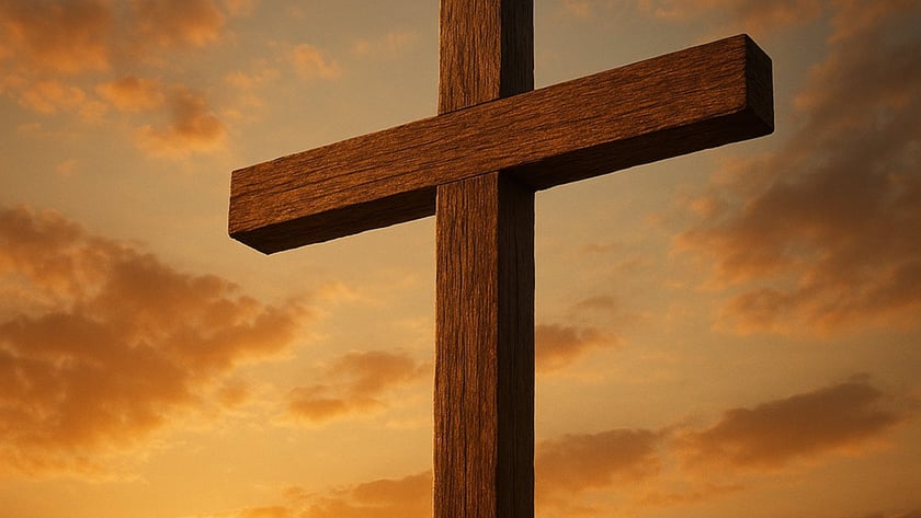 Cruz de madeira rústica contra o céu alaranjado com nuvens e o sol baixo.