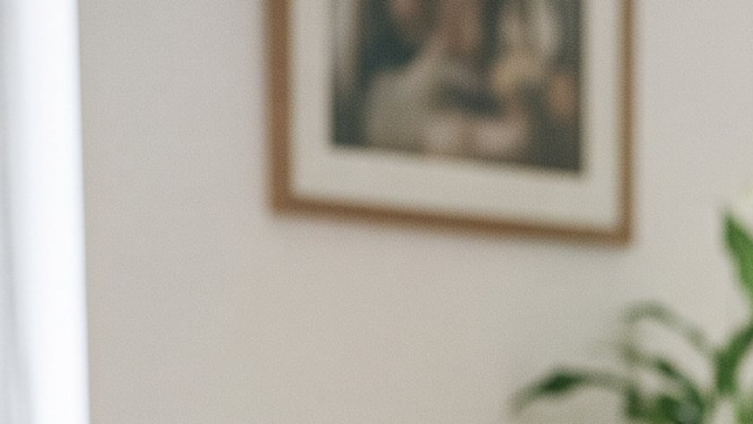 Mulher de olhos fechados, com as mãos sobre uma Bíblia aberta, à mesa de uma sala.