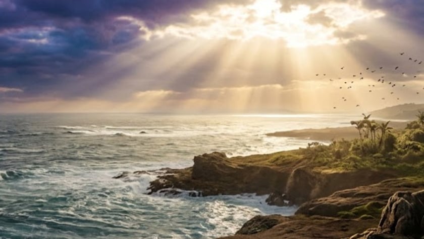 Costa rochosa com vegetação tropical, mar agitado e raios de sol entre nuvens escuras.
