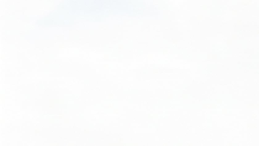 Homem barbado de jaqueta segura um livro junto ao peito em um morro com campos ao fundo