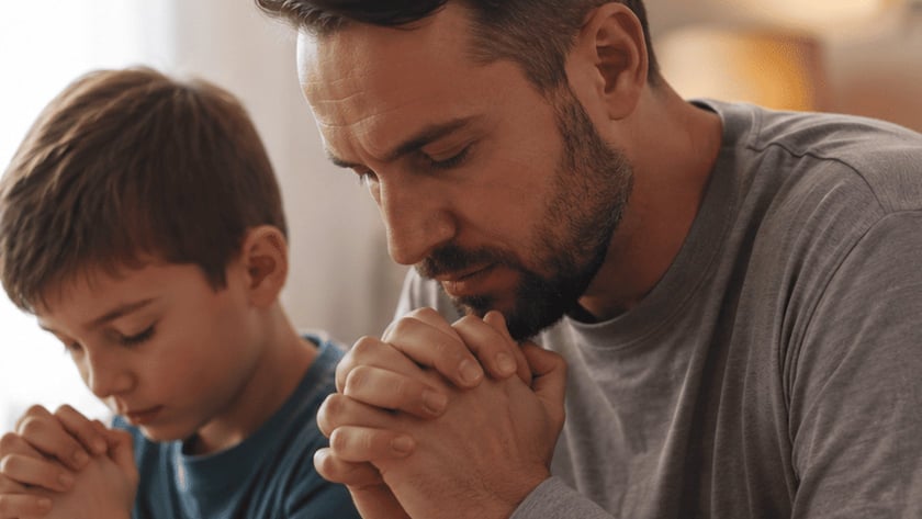 Homem e menino de mãos postas e olhos fechados, rezando lado a lado em um quarto.