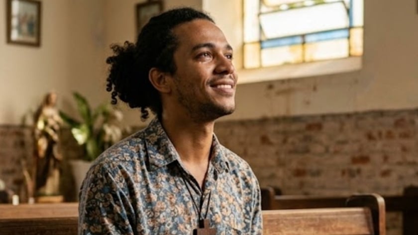 Homem sentado em um banco de igreja, com uma Bíblia aberta no colo e as mãos unidas.