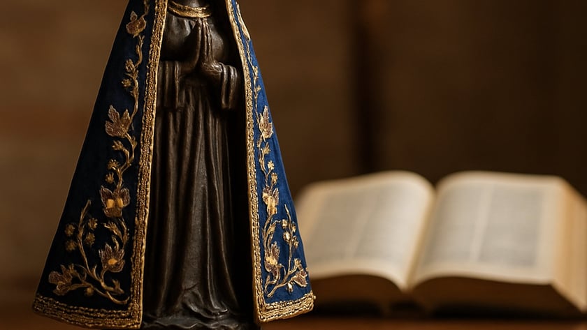 Estatueta de santa com coroa dourada e manto azul bordado, diante de uma Bíblia aberta.