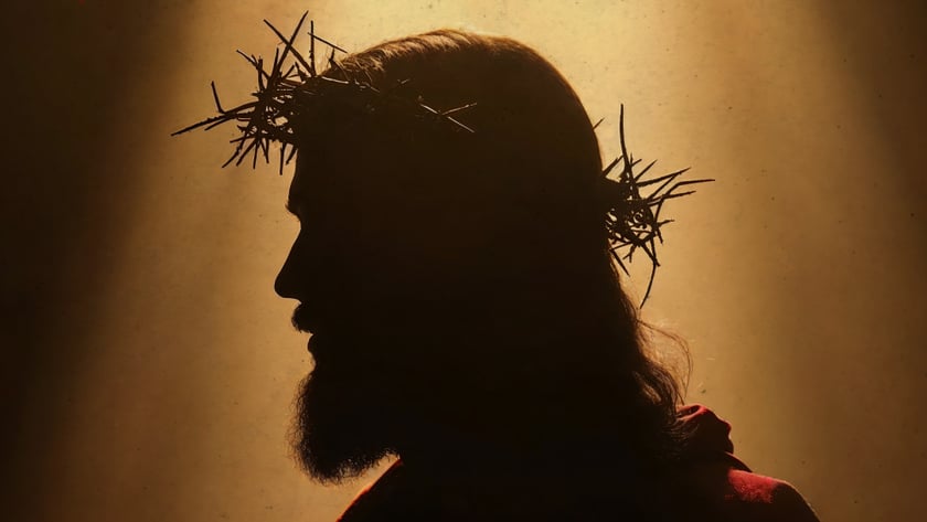 Silhueta de homem barbudo de perfil, com coroa de espinhos e manto avermelhado.